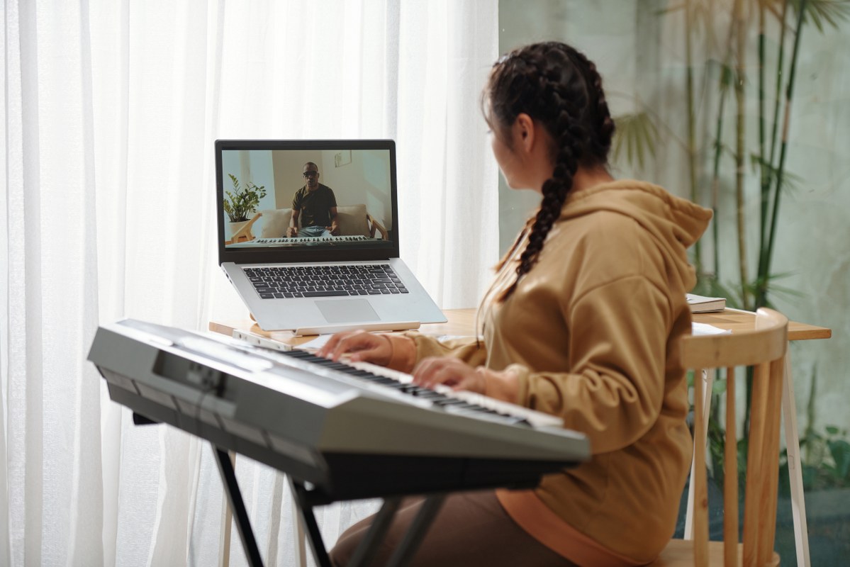 Teenage girl listening attentively to piano teacher on screen.