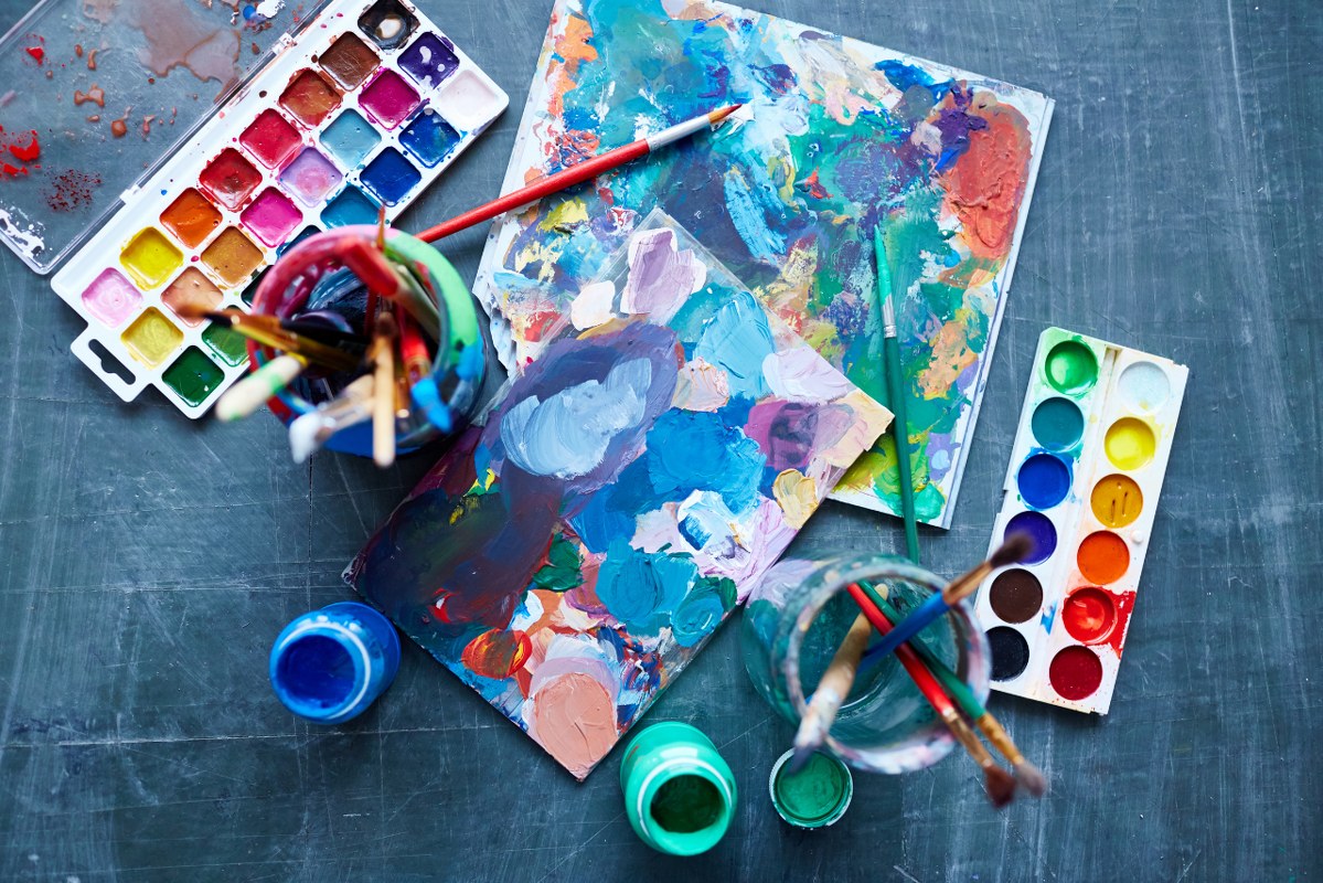 Top view of paints, palettes, and brushes.