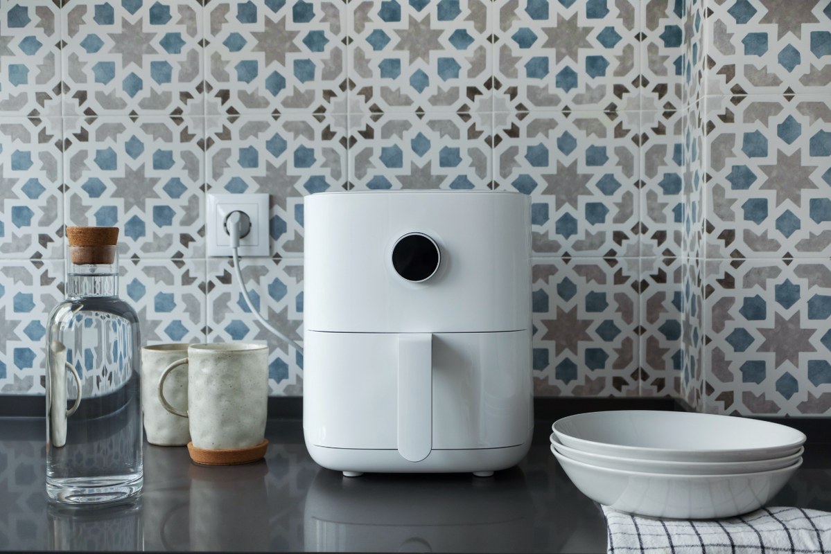 White air fryer with other kitchen items on modern domestic kitchen.