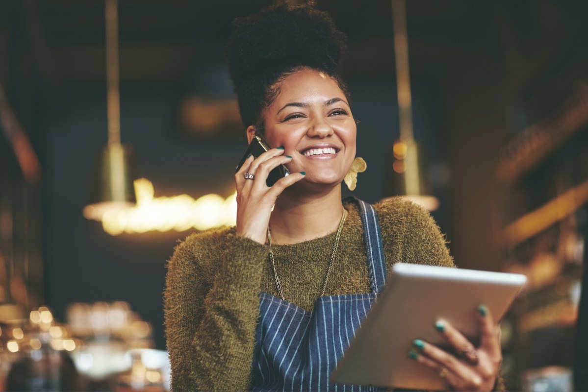 Woman happily talks with a supplier over the phone.