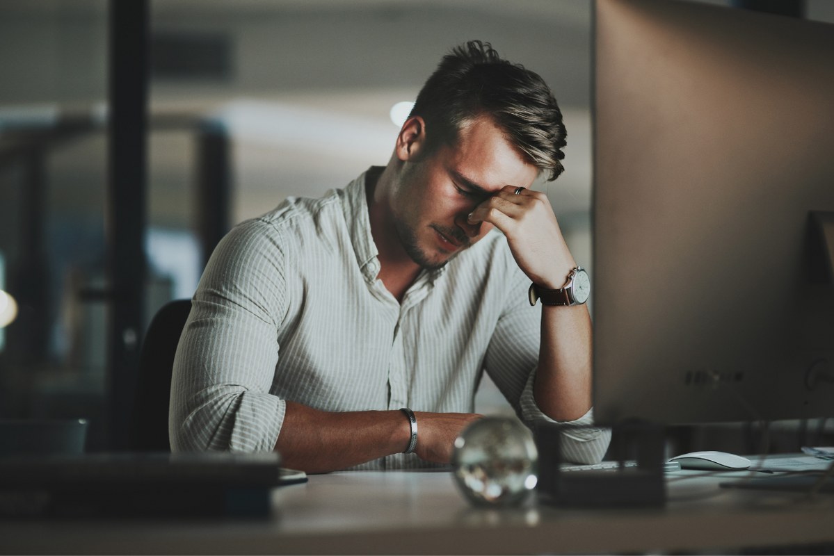Young businessman looking down, stressed while working on computer.