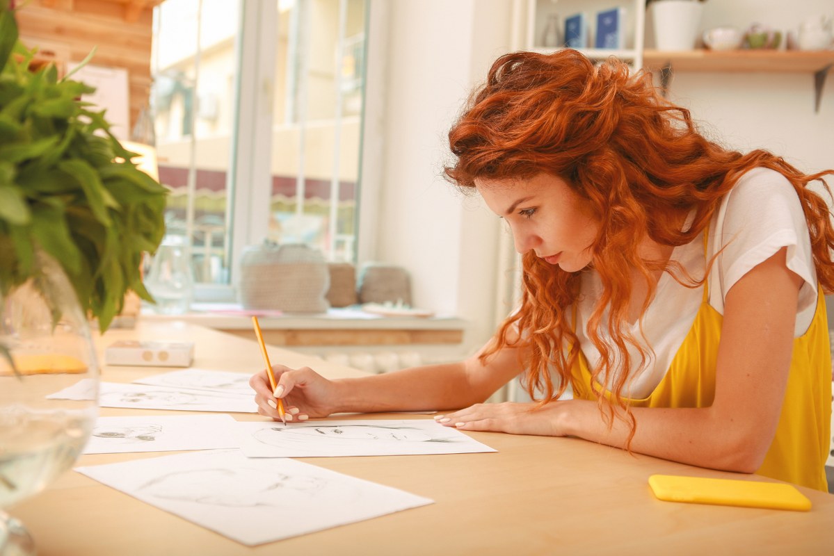 Young woman draws clothes sketches on paper.