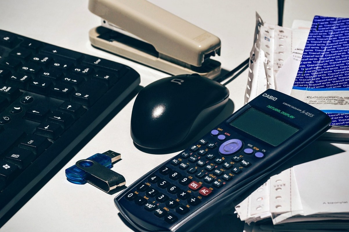A calculator, a mouse, and a keyboard on a desk.