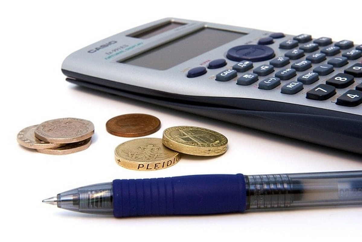 A calculator, a pen and coins on a surface.