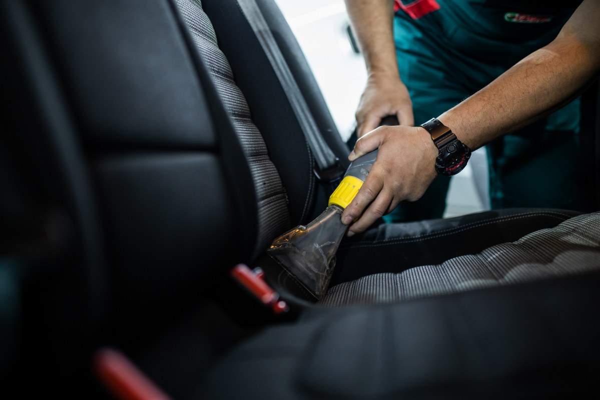 A car detailing professional performing deep interior cleaning.