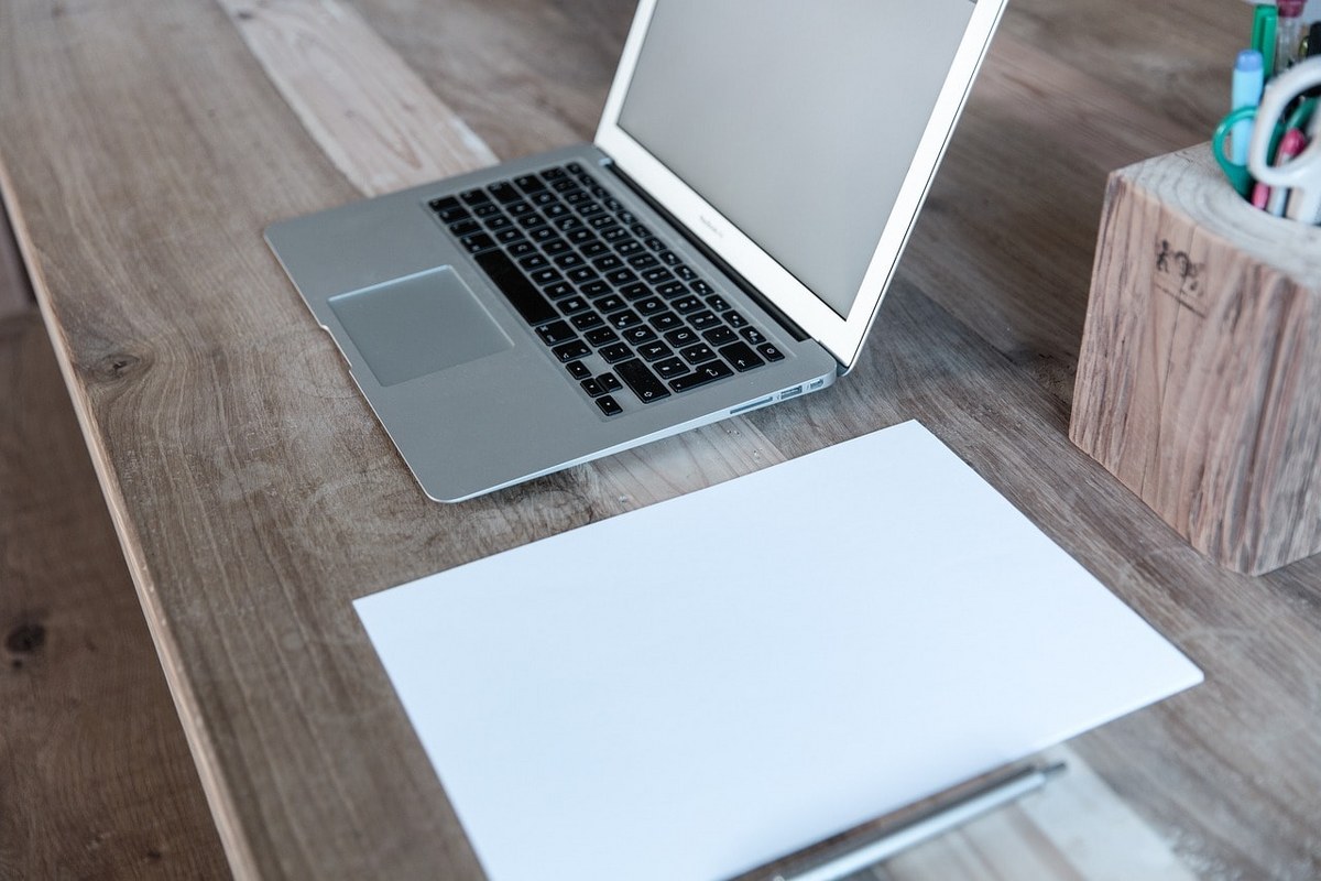 A laptop and a blank piece of paper.