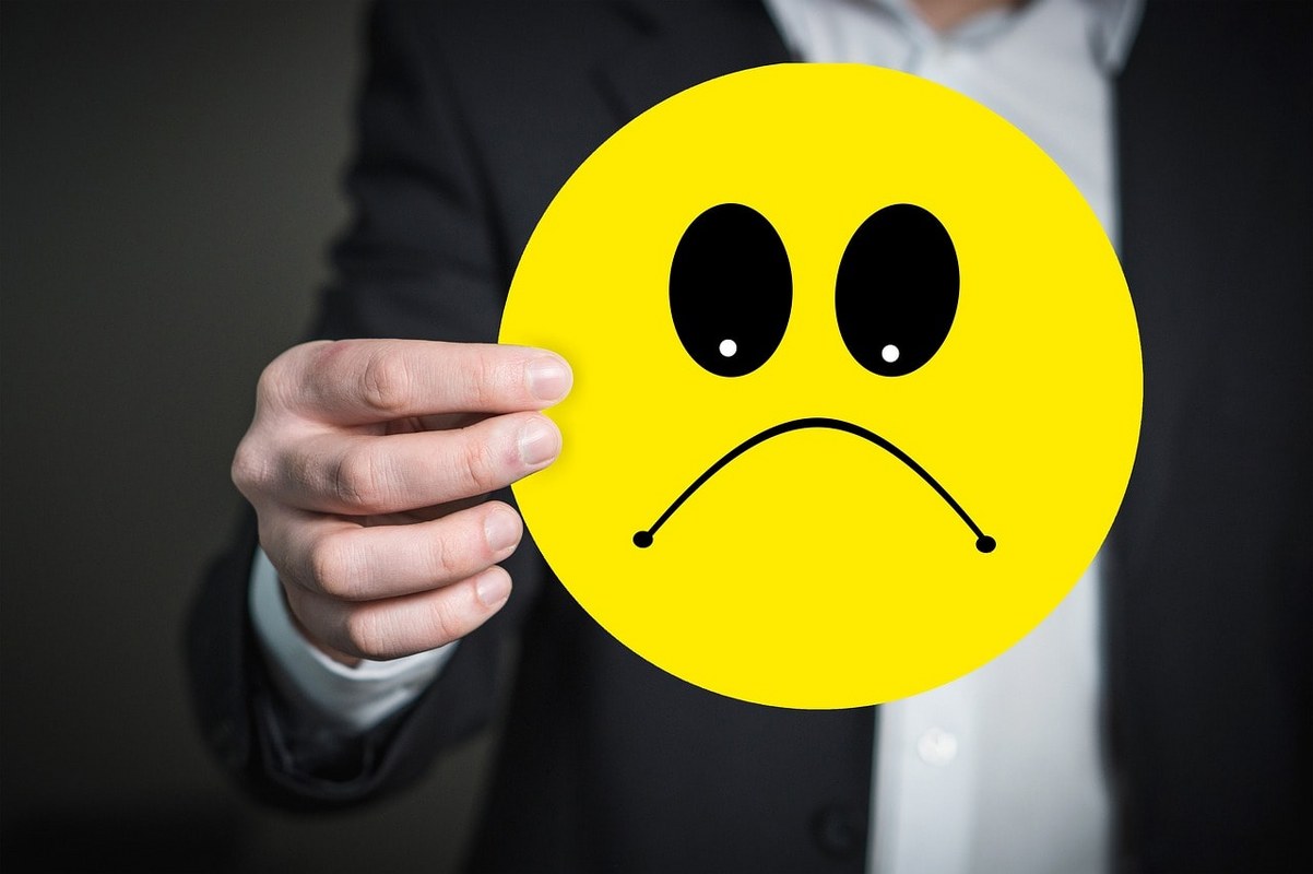 A man holding an emoji showcasing a bad mood.
