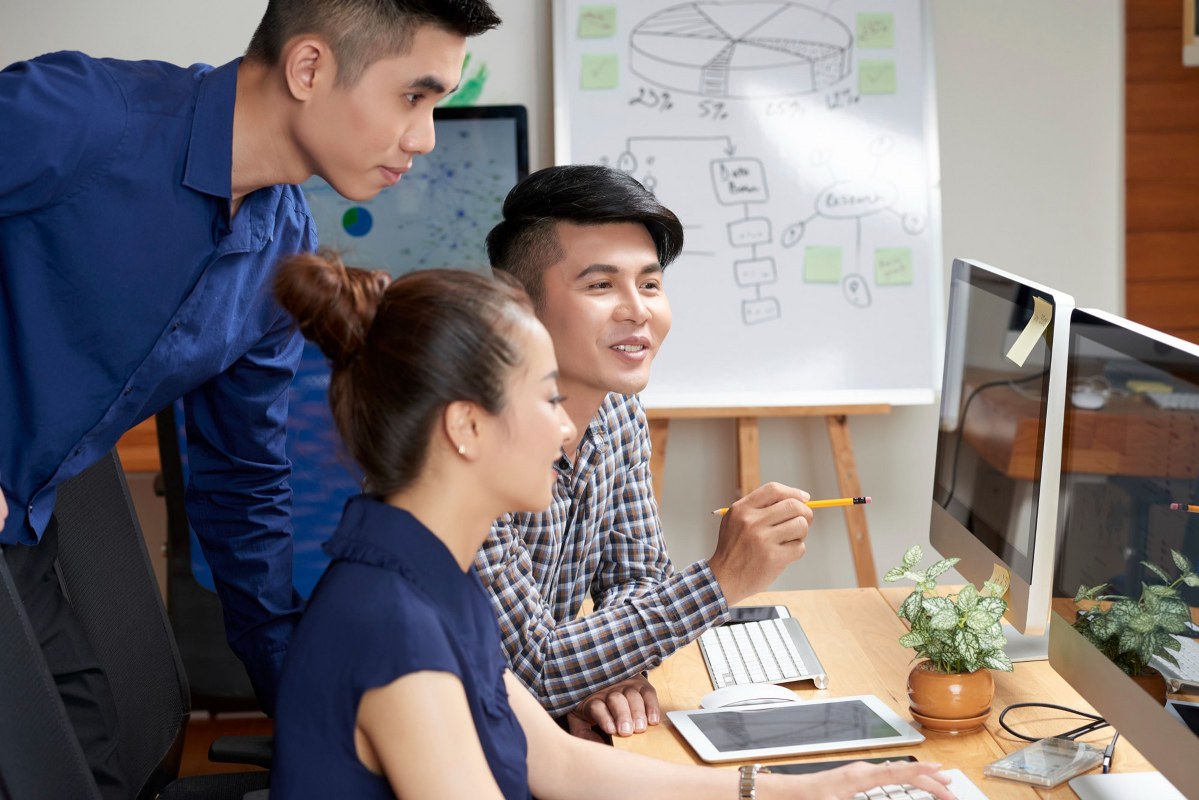 A man is mentoring two colleagues a project.