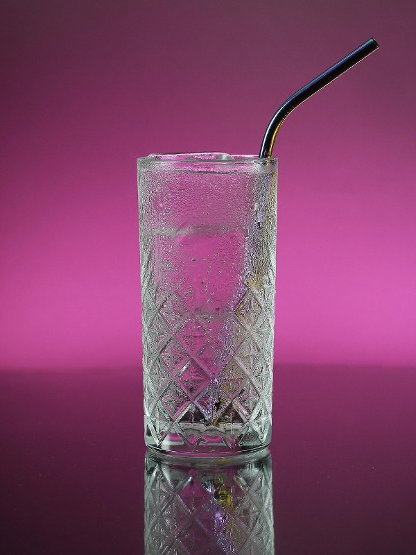 A metallic straw inside a glass bottle.