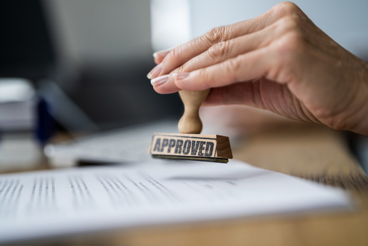 A person is approving a document with a stamp.
