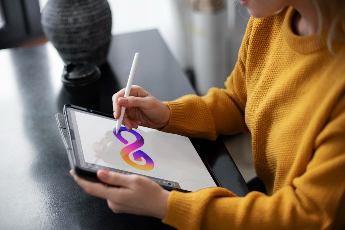 A woman is drawing a logo on a graphic tablet.