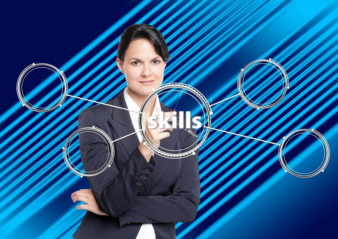 A woman pointing at the word skills which are acquired after practice.