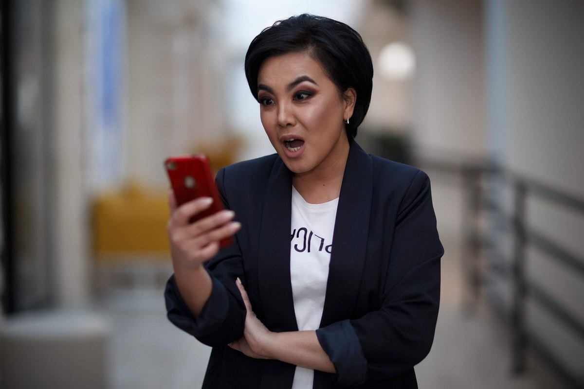 A woman suprised as she looks into her phone.