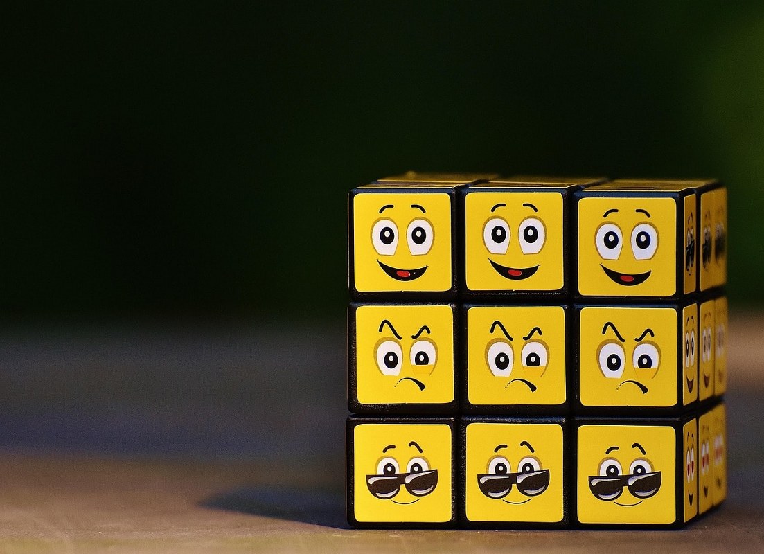 A yellow dice showing different emotions.
