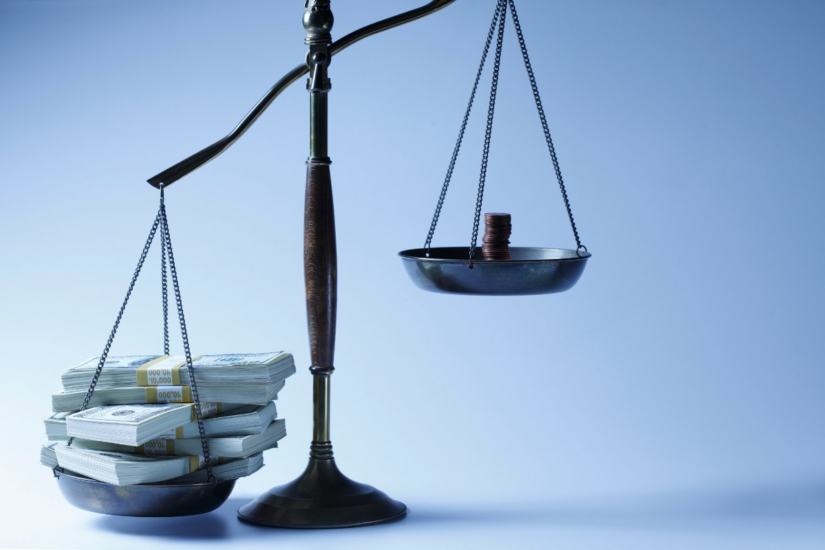 An unbalanced scale: one side piled with money, the other with just pennies.