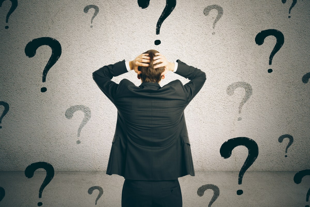 Backview of confused businessman with questions marks as background.