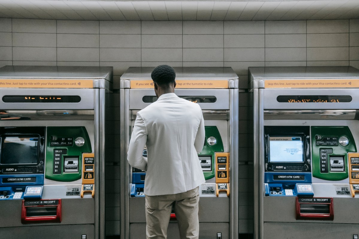 Backview of male atm owner infront of machines.