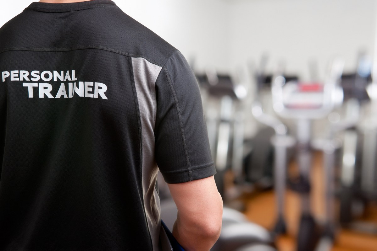 Backview of male personal Trainer At The Gym.