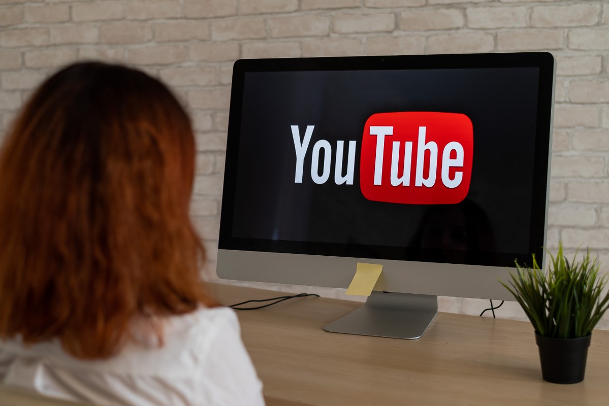 Backview of young woman watching youtube on dekstop.