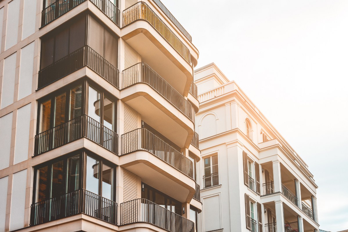 Beautiful new apartment building with modern facade and warm sunlight.