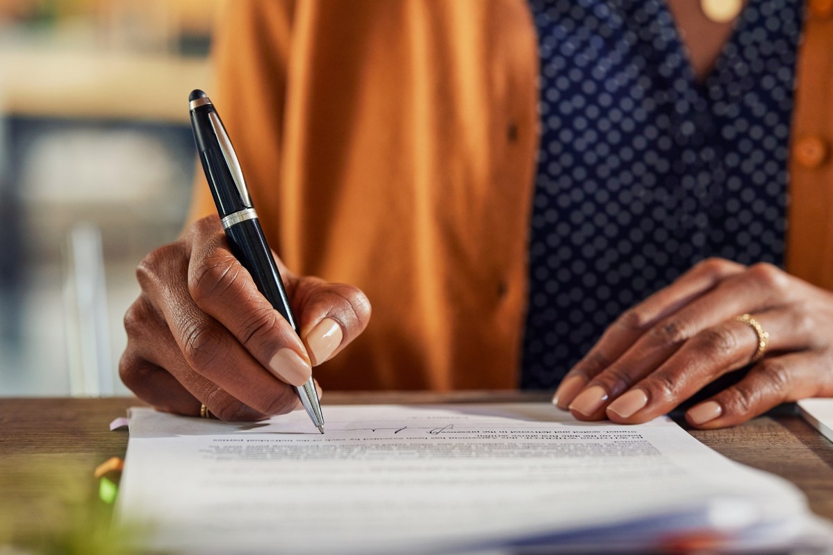 Black woman signing less paper.
