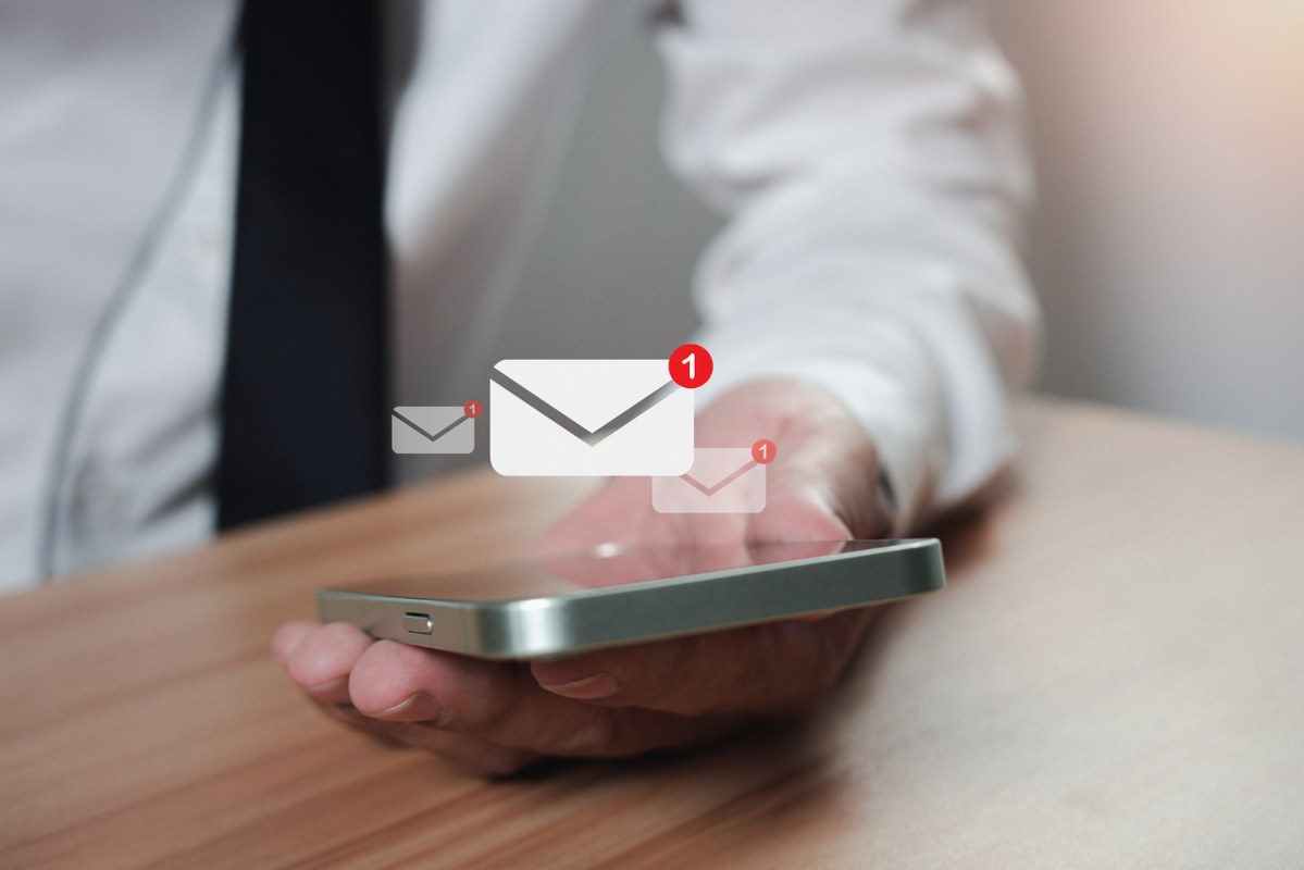 Businessman holding a phone along with the e-mail icon. 