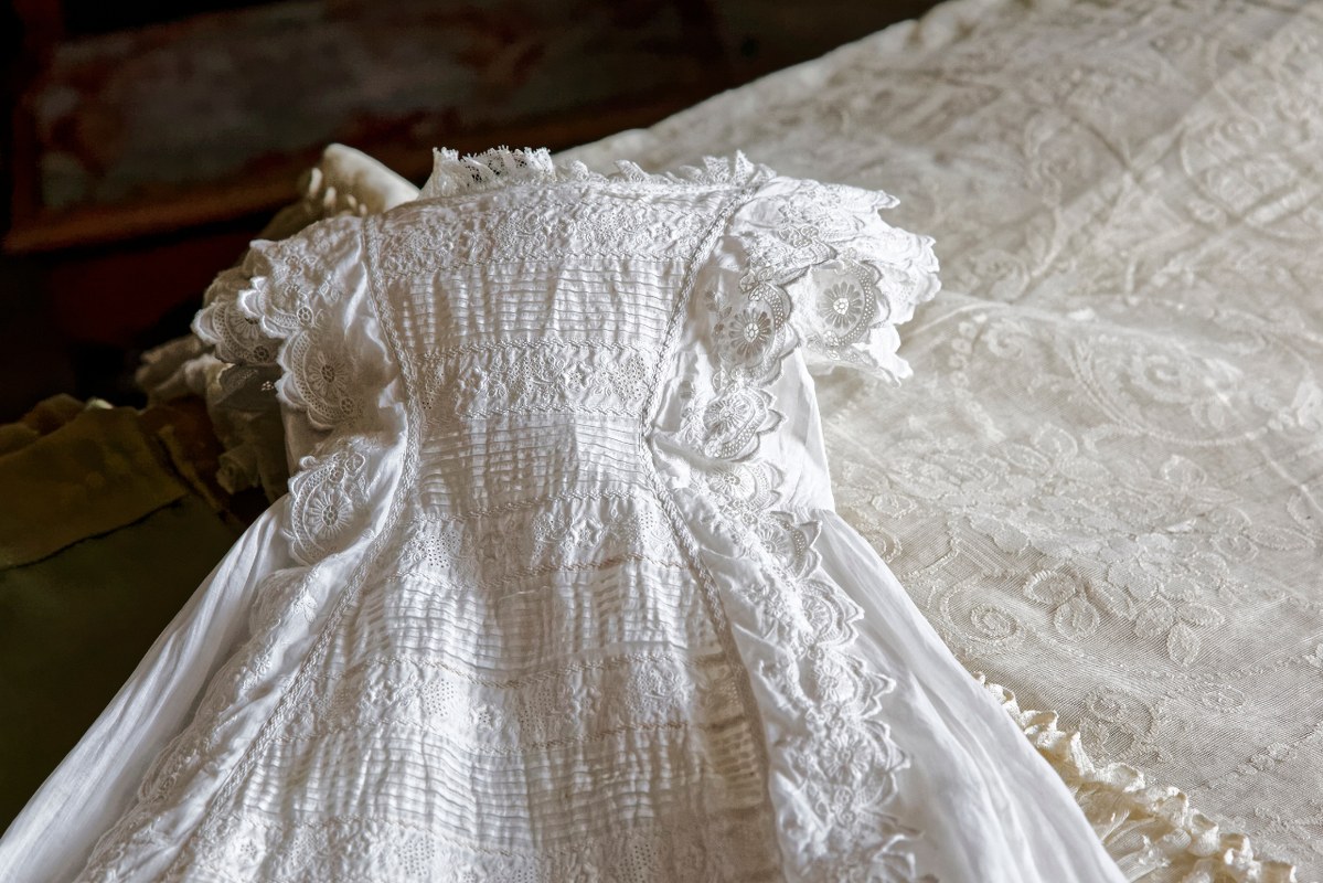Christening gown lay on bed.