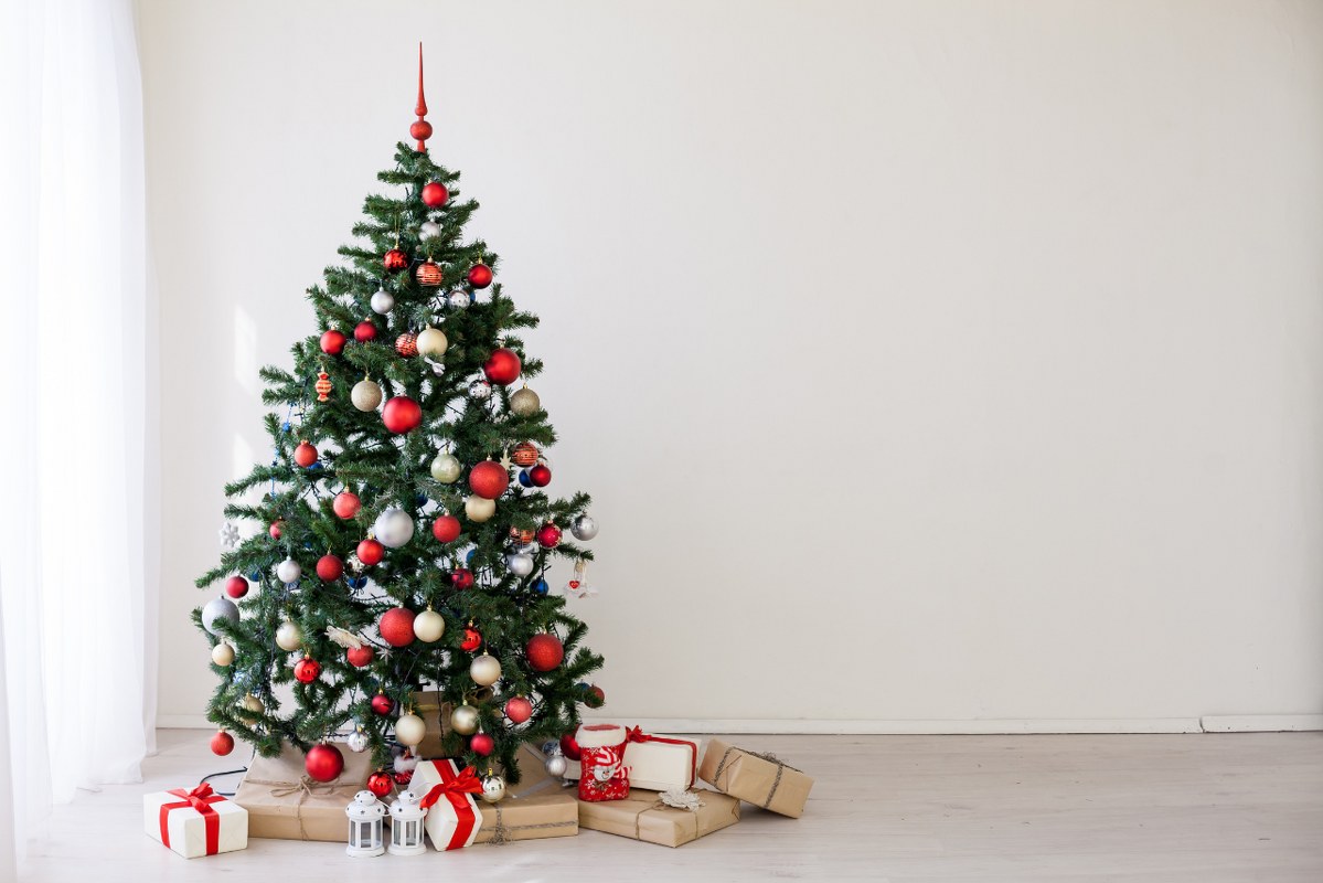 Christmas tree with red gifts in the white room.