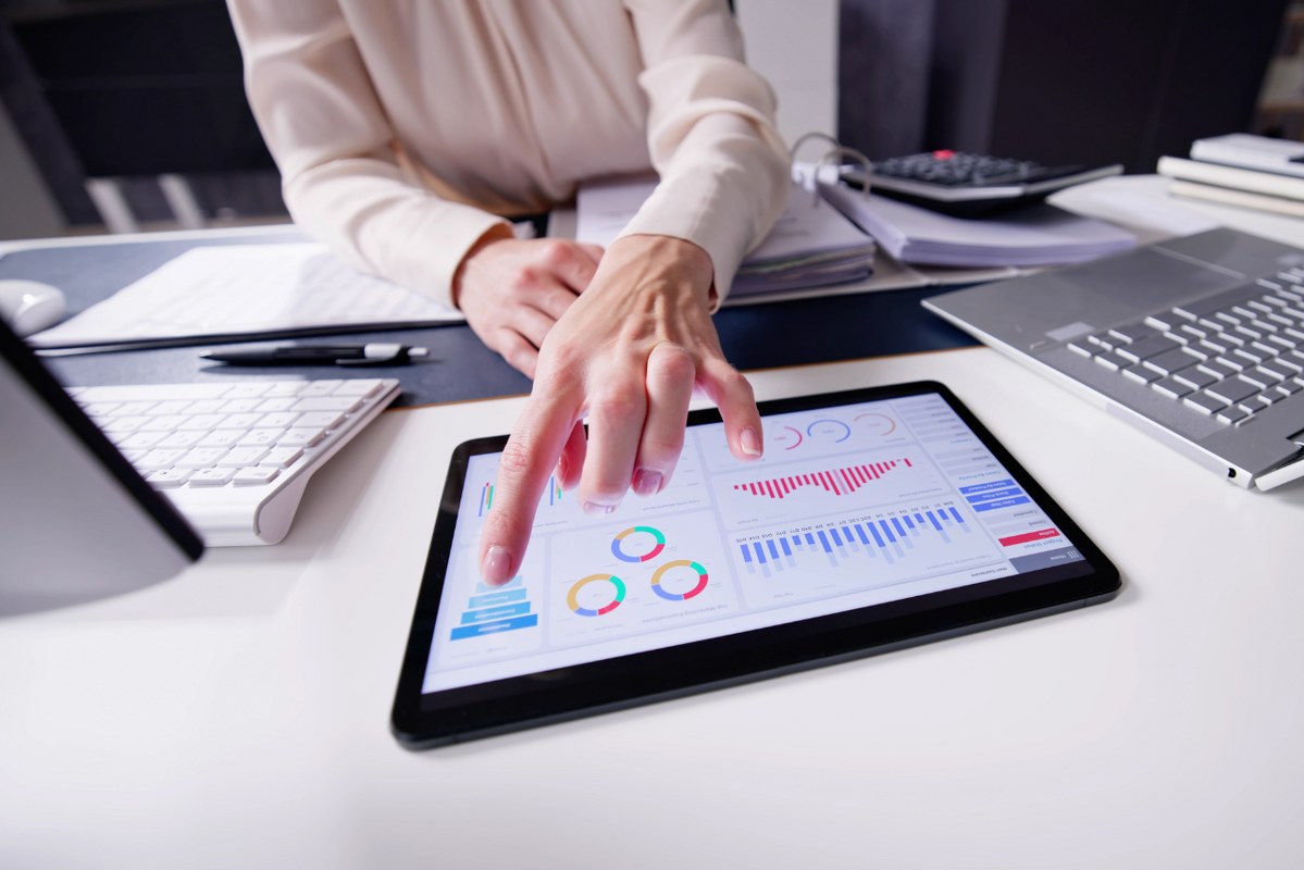Close-up of female business woman's index finger on analytical data from tablet screen.