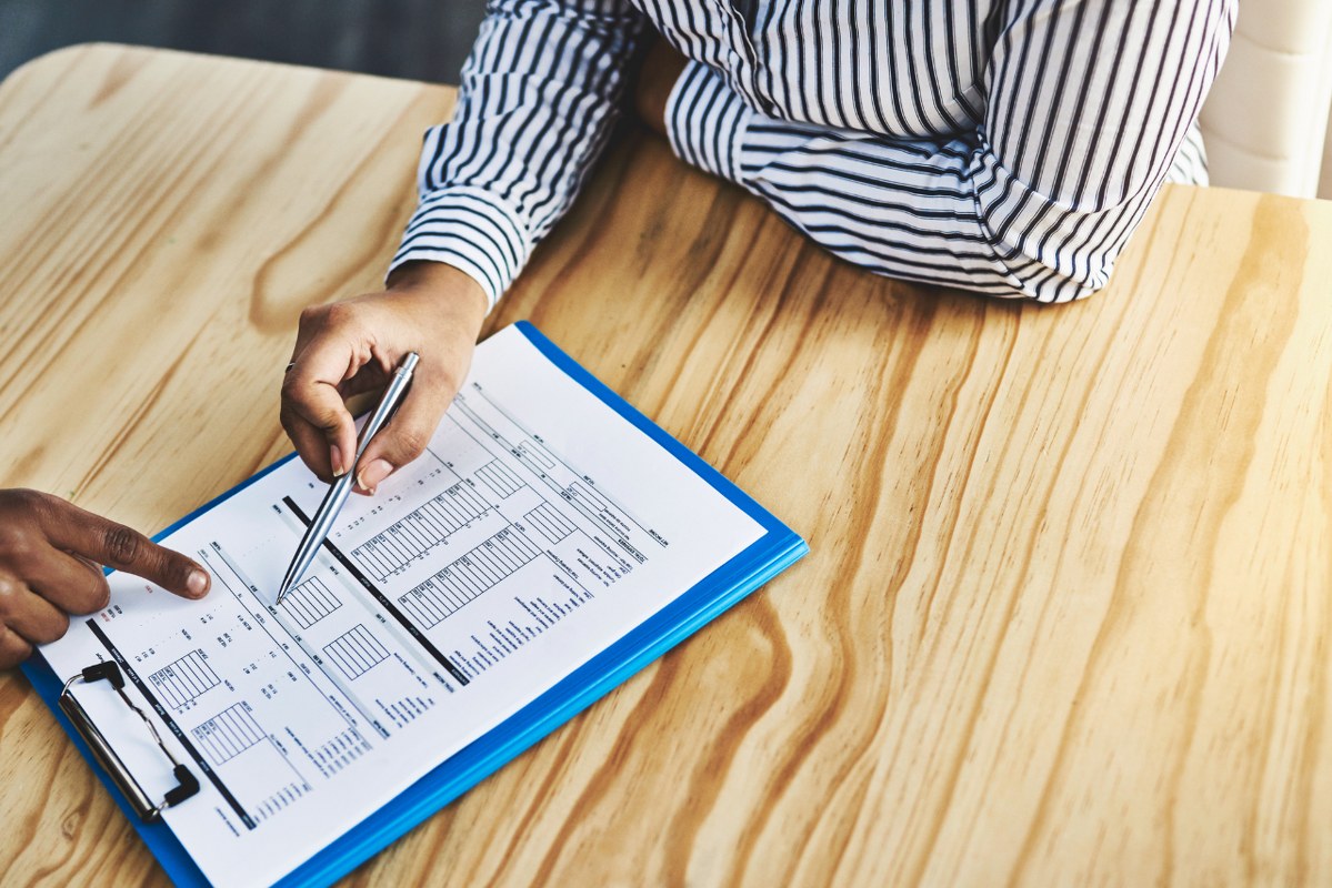Close up of two business people reviewing document on table.