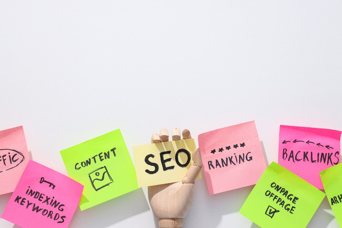 Colored papers with SEO and related words and wooden hand on white background.