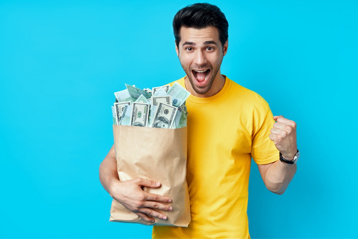 Delivery man holding grocery bag full of money.