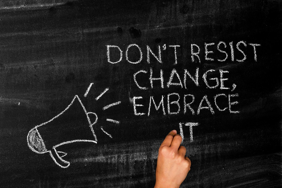 Don't resist change embrace it message written by hand using chalk.