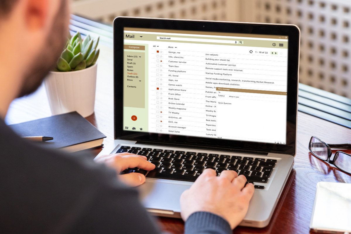 Emails list on a laptop screen, office workspace.