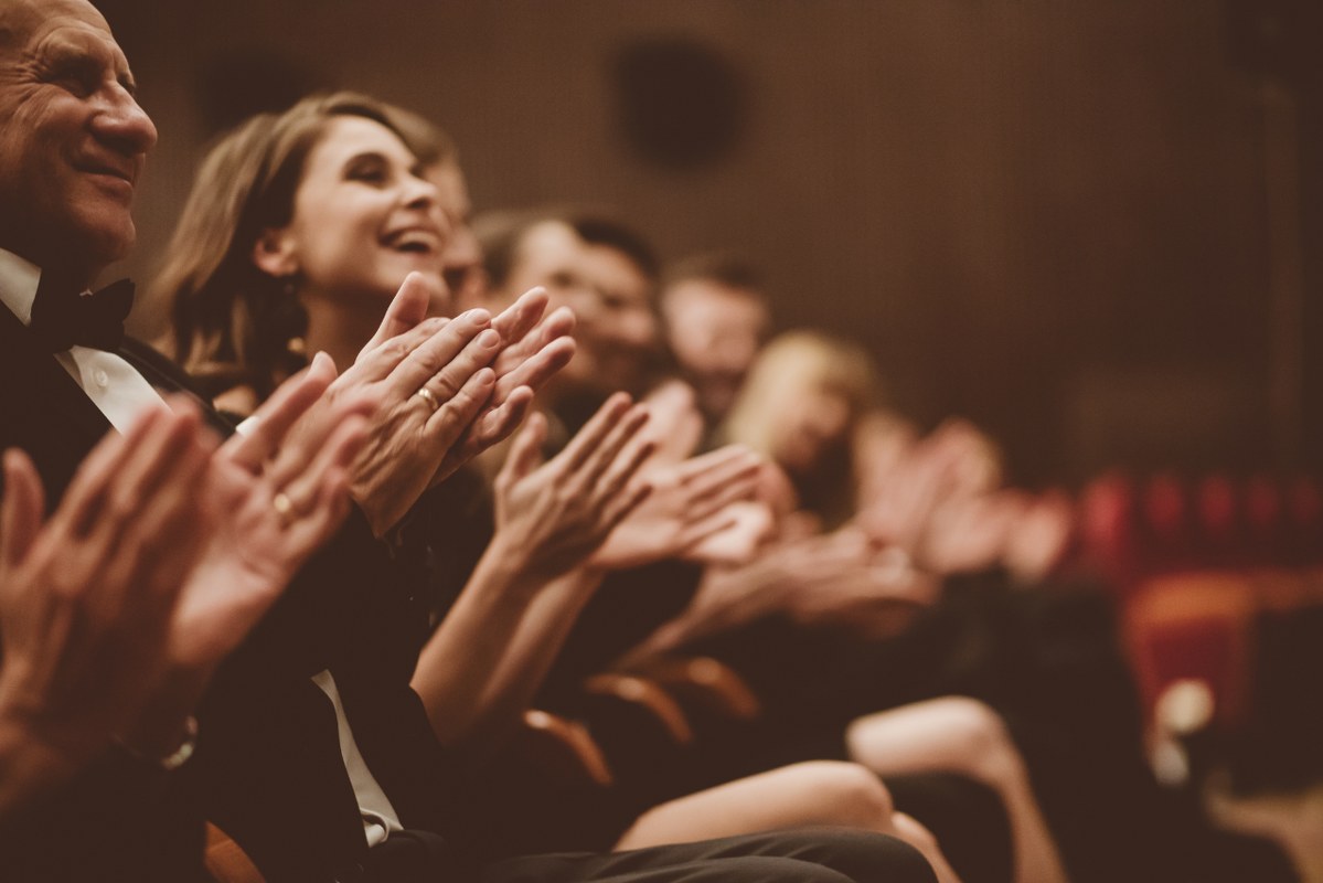Excited audience clapping in the theater.