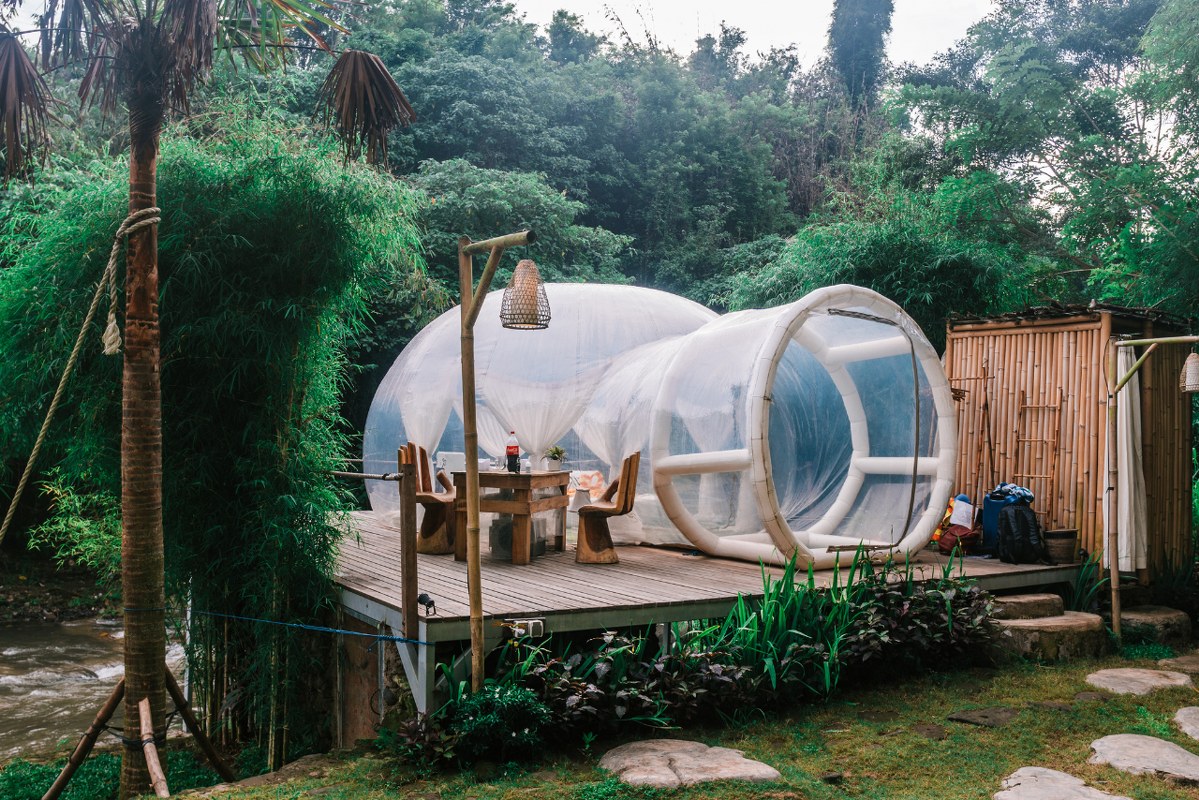Exterior of cute bubble tent, glamping in tropical garden.