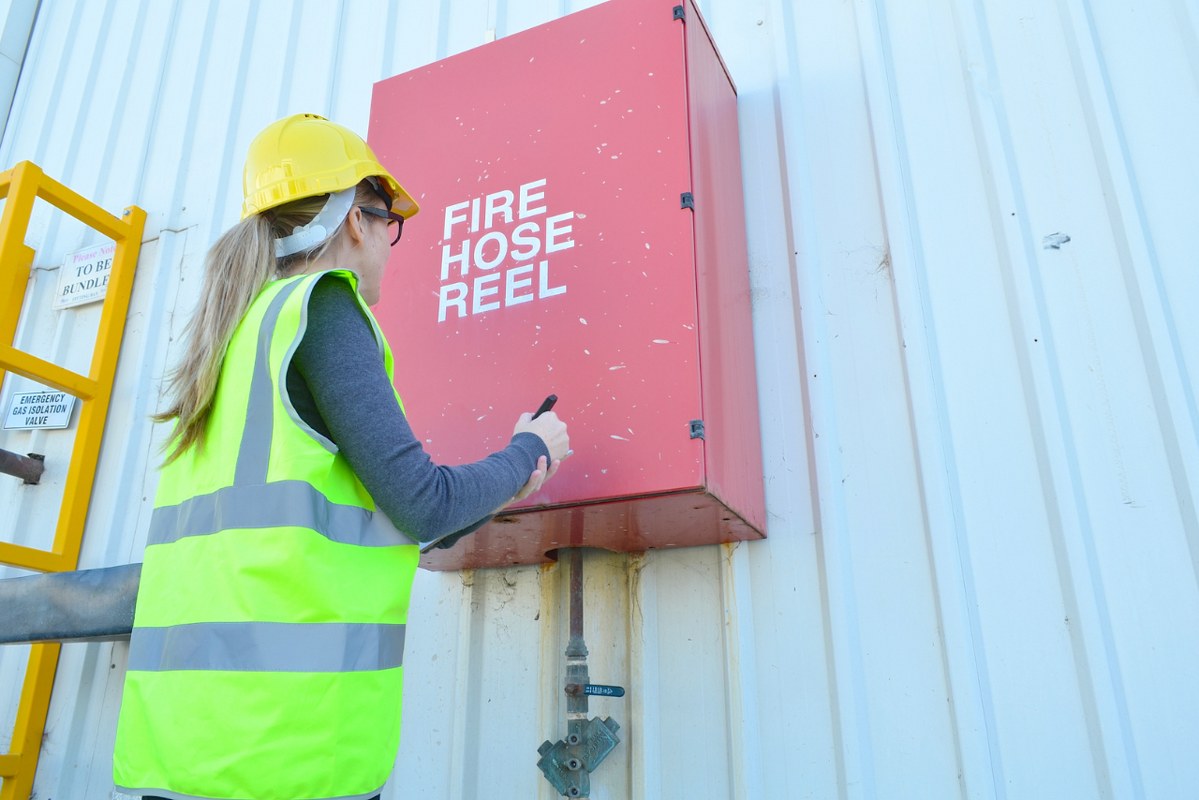 Femal fire inspector checking fire hose.