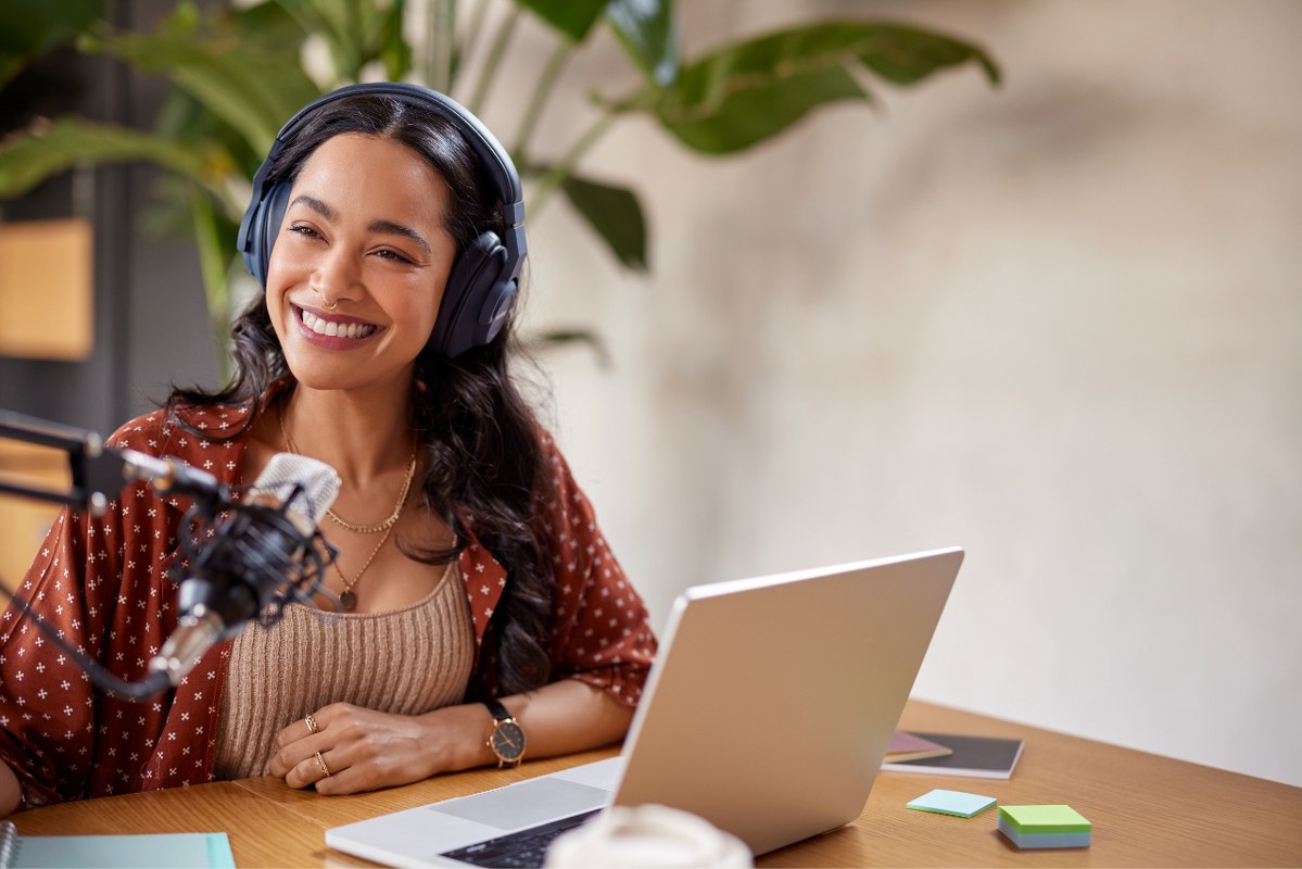 Female podcaster doing an episode using laptop and condenser.