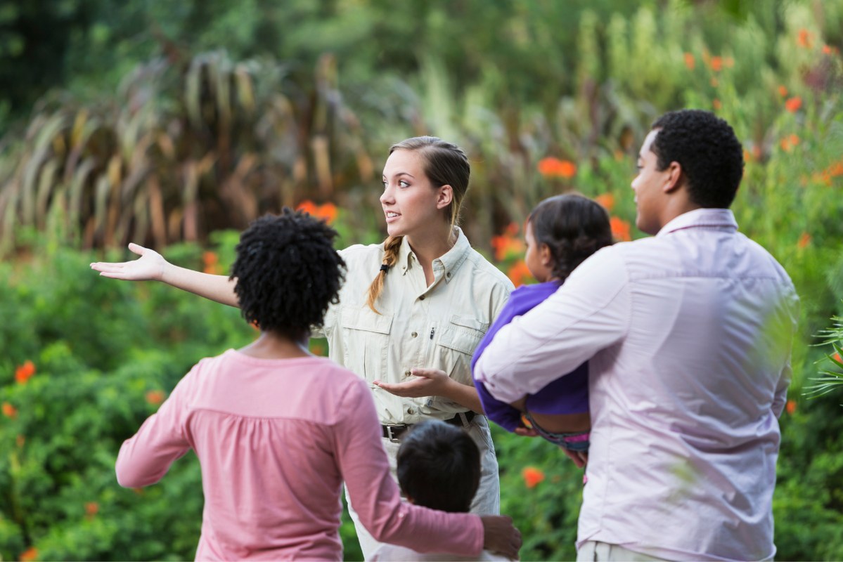 Female tour guide showing family the way.