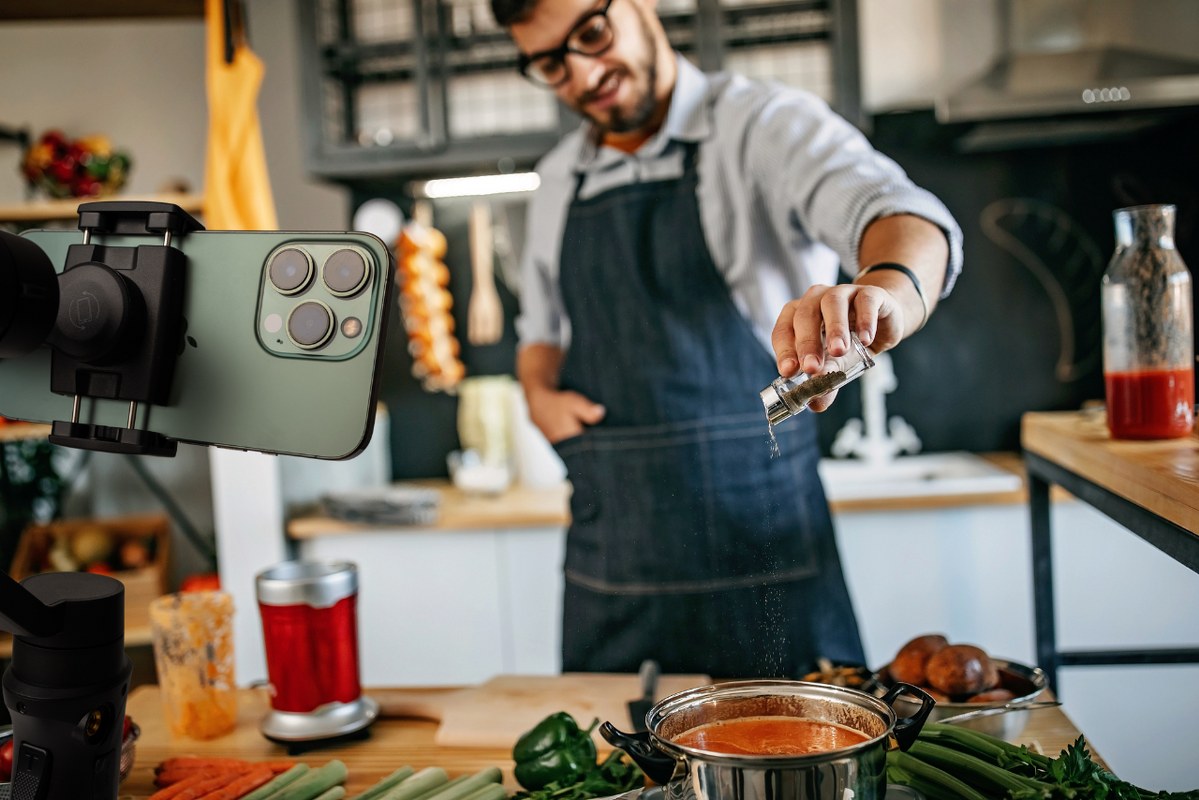 Food blogger using spice while recording on phone.