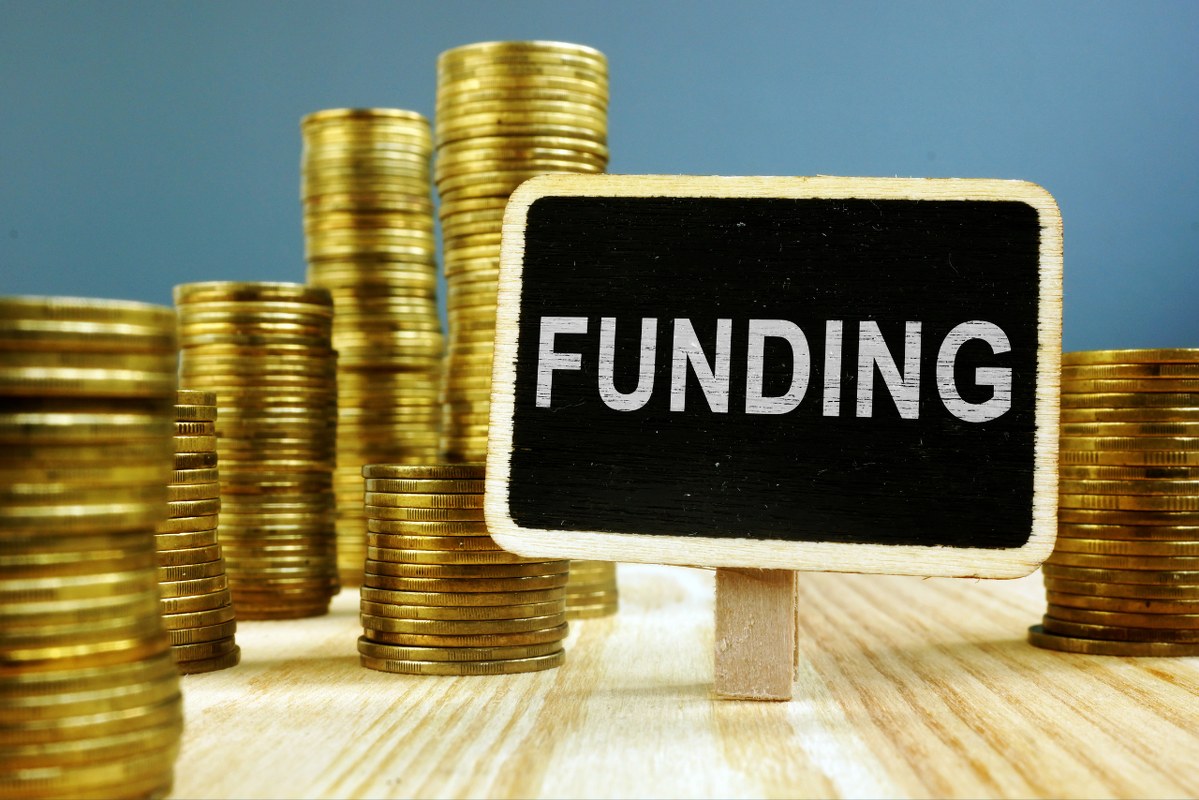 Funding concept: Coins stack on wooden surface.