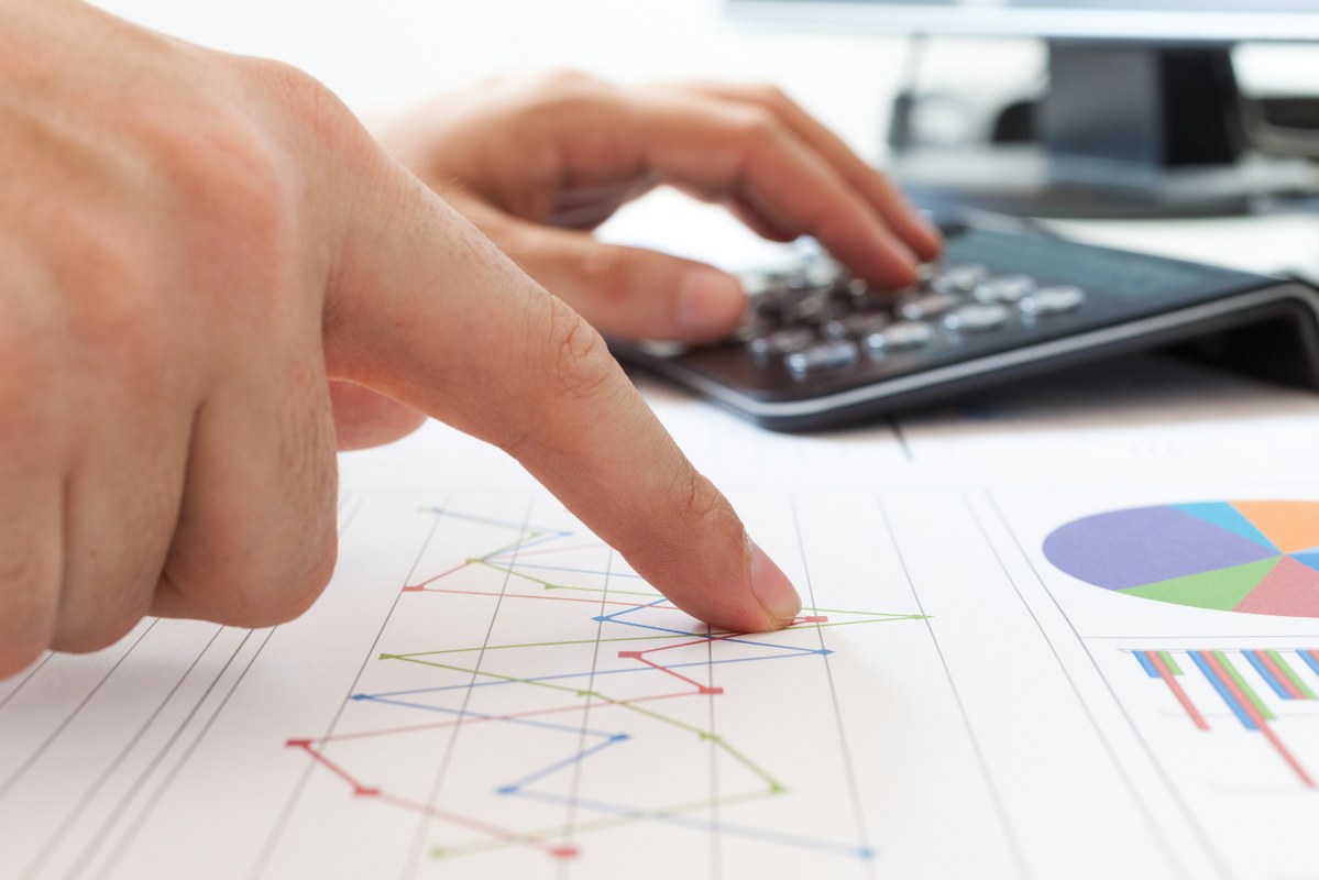 Hand pointing on market trend chart with calculator for cost.