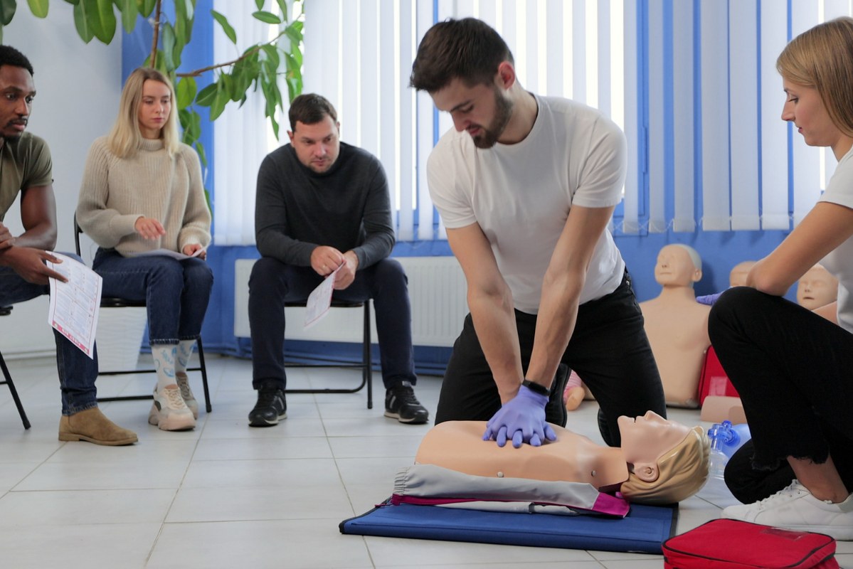 Instructor Demonstrating CPR on Mannequin at First Aid Training Course.