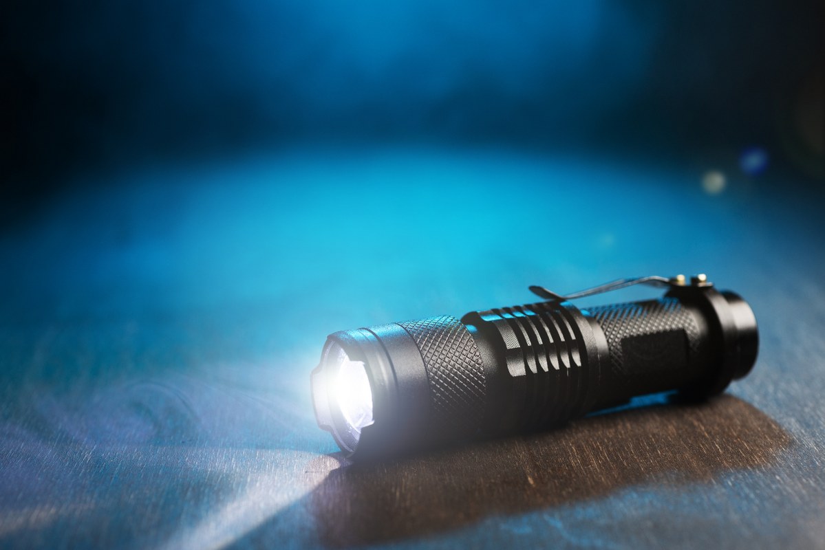 LED flashlight shines on the table in smoke.