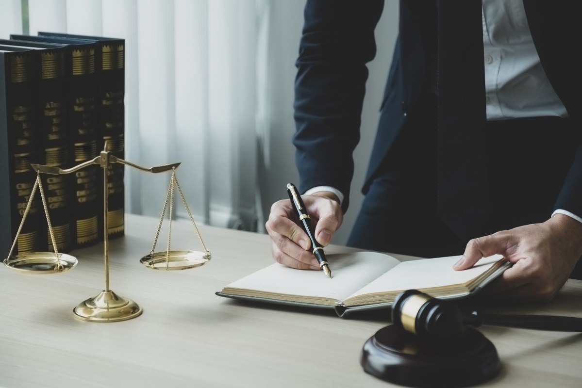 Lawyer hand holding pen and providing legal consult business at the office.
