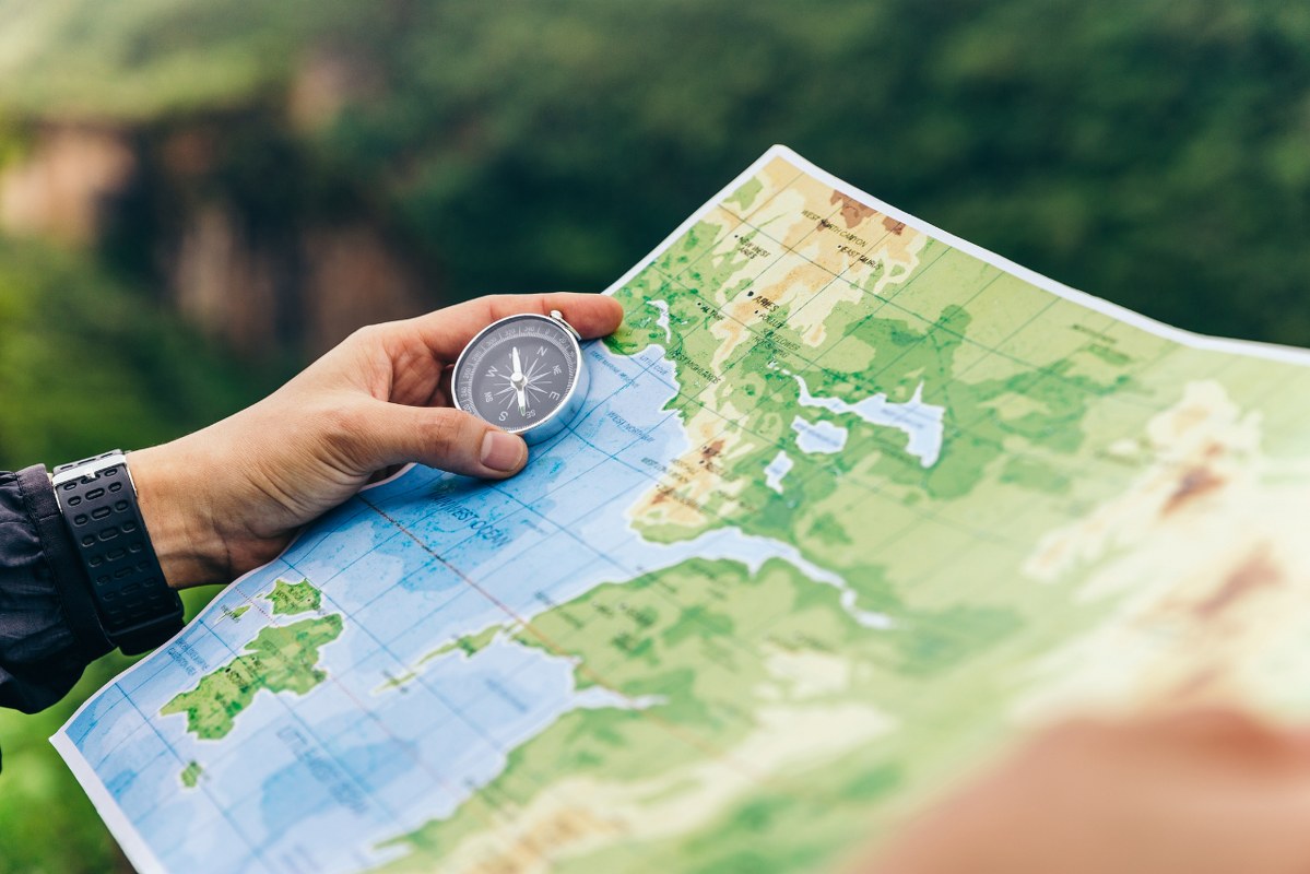 Location concept: compass and map in hands of traveler.
