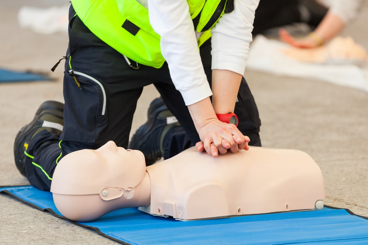 Low Section Of Paramedic Practicing Cpr While Sitting On Floor.
