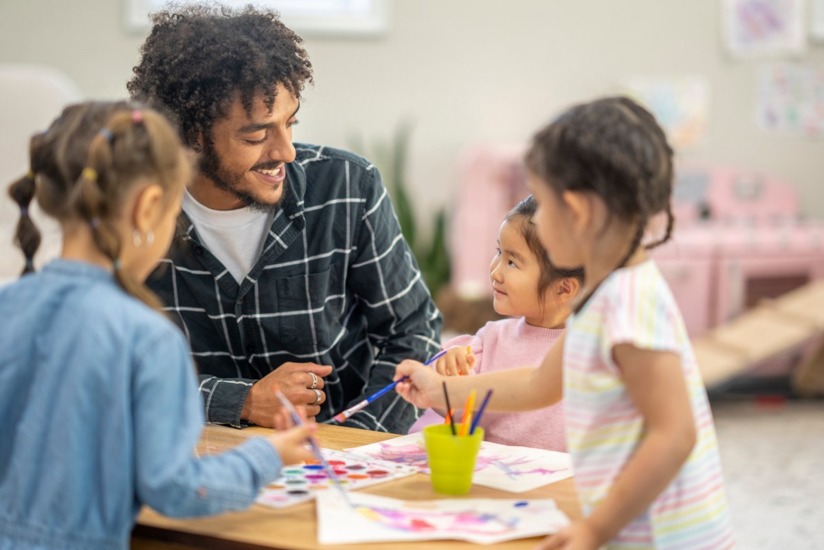 Male Childcare Working Facilitating Painting.