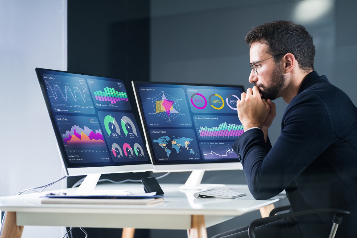 Male Quantitative Analyst focusing on multiple monitors.