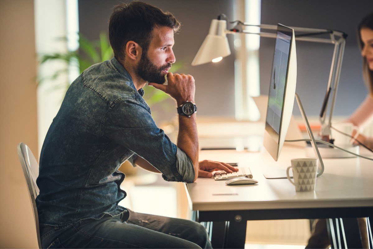 Male person focused on computer, studying market trends in industry.